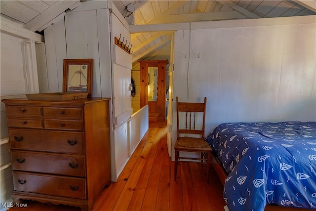 bedroom with hardwood / wood-style floors, lofted ceiling with beams, wooden ceiling, and wooden walls