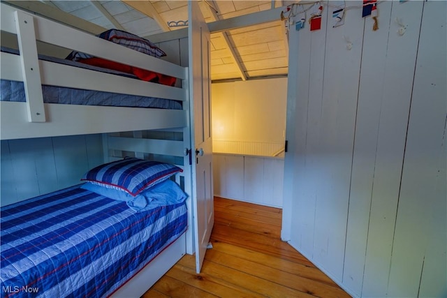 bedroom featuring light wood-type flooring and wooden walls