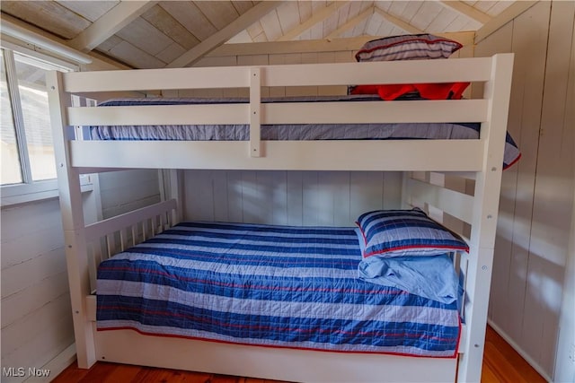 bedroom with hardwood / wood-style flooring, vaulted ceiling with beams, and wood walls