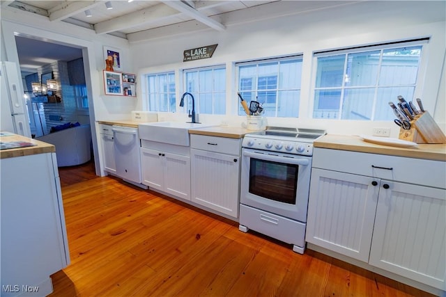 kitchen with beam ceiling, light wood-type flooring, white appliances, and sink