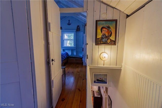 hallway featuring hardwood / wood-style floors, wood walls, and lofted ceiling