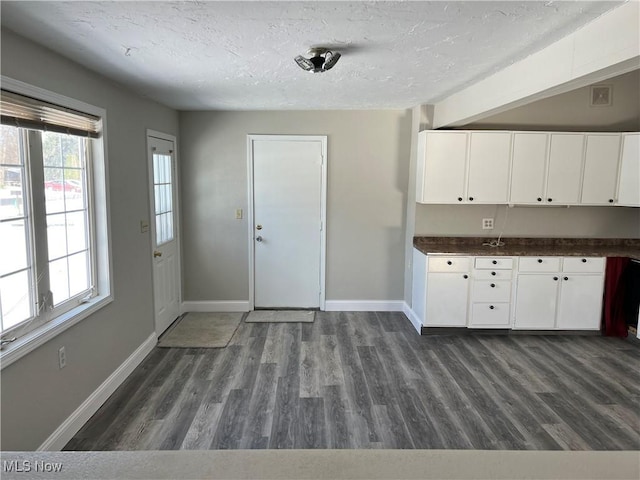 kitchen with white cabinets, dark wood-type flooring, and a textured ceiling