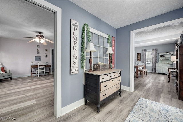 hall featuring a textured ceiling and light hardwood / wood-style floors