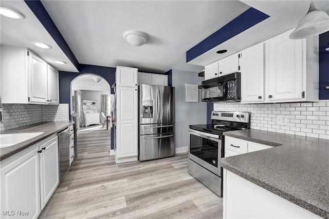 kitchen featuring white cabinetry, stainless steel appliances, backsplash, pendant lighting, and light hardwood / wood-style floors