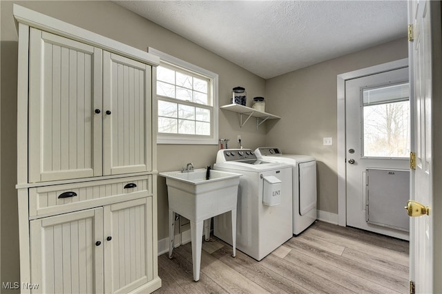 laundry room featuring washing machine and dryer, a textured ceiling, and light wood-type flooring