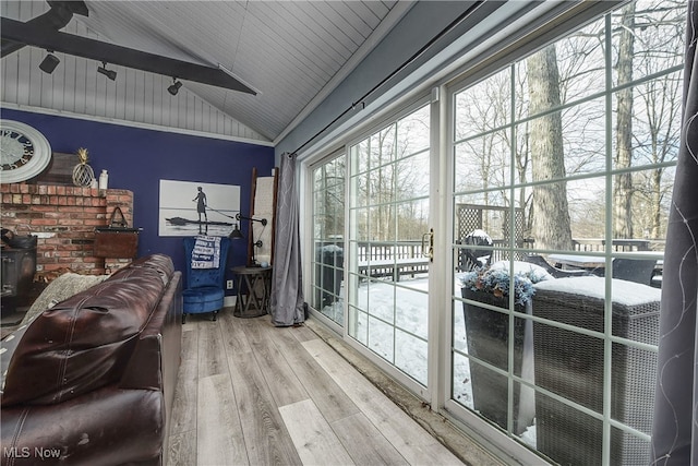 interior space with wood ceiling, vaulted ceiling with beams, wood-type flooring, and a wood stove