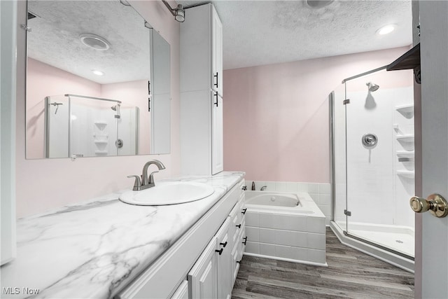 bathroom featuring hardwood / wood-style flooring, shower with separate bathtub, and a textured ceiling