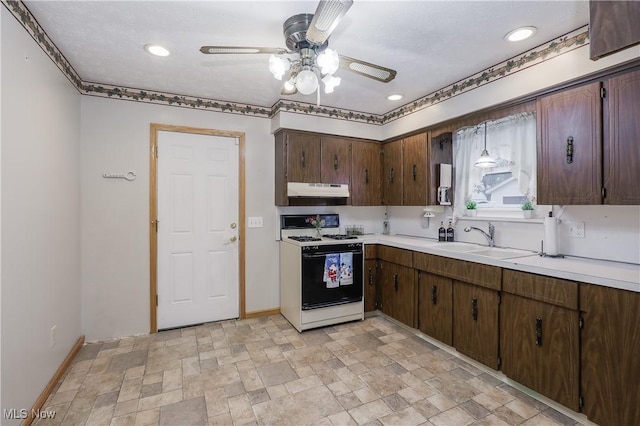 kitchen featuring ceiling fan, white range with gas cooktop, pendant lighting, dark brown cabinetry, and sink