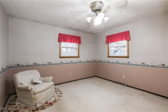 living area with a textured ceiling, ceiling fan, and carpet floors