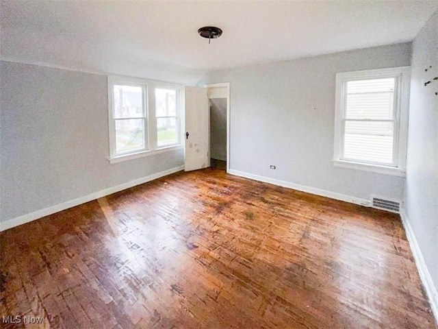 empty room featuring hardwood / wood-style flooring, a healthy amount of sunlight, and vaulted ceiling