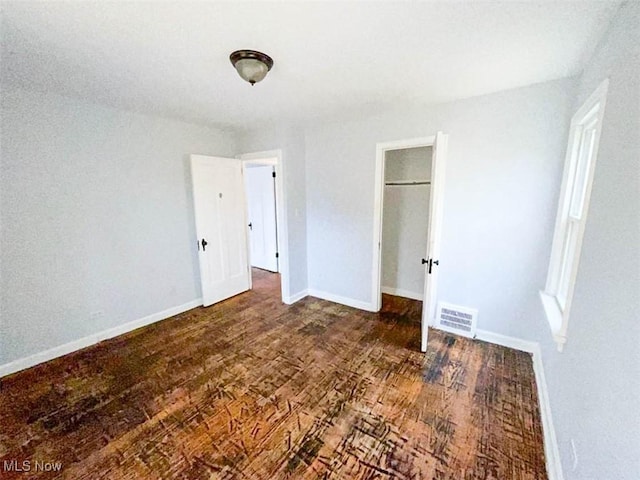 unfurnished bedroom featuring a closet and dark hardwood / wood-style flooring