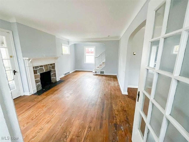 unfurnished living room with a stone fireplace and hardwood / wood-style flooring