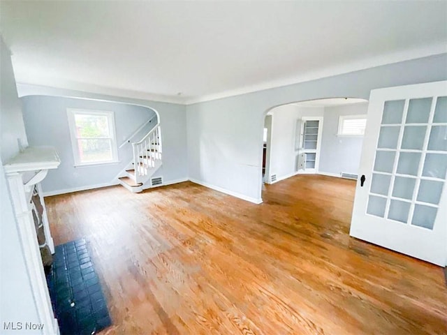 unfurnished living room featuring wood-type flooring and a brick fireplace