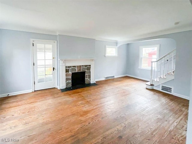 unfurnished living room featuring a stone fireplace and hardwood / wood-style floors