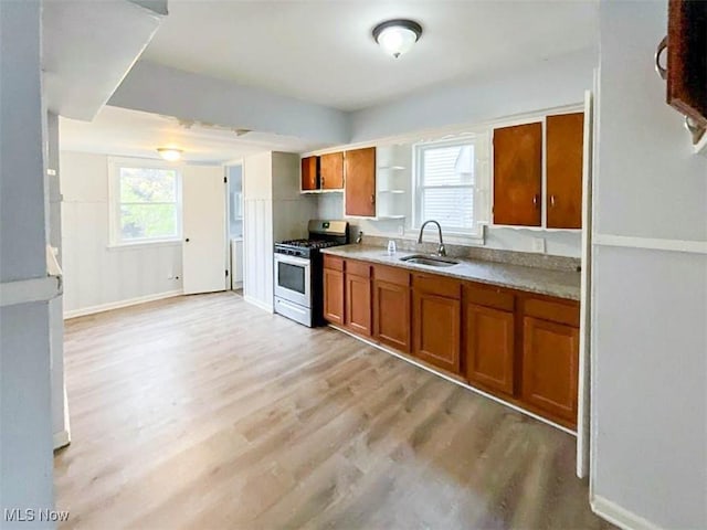 kitchen featuring light wood-type flooring, stainless steel gas stove, and sink