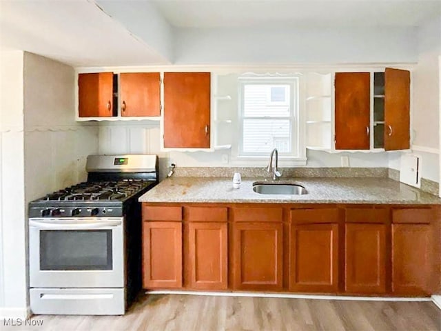 kitchen featuring light stone counters, sink, light hardwood / wood-style floors, and white gas range oven