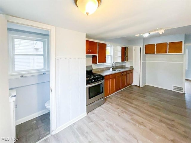 kitchen featuring light wood-type flooring, stainless steel range with gas cooktop, a wealth of natural light, and sink