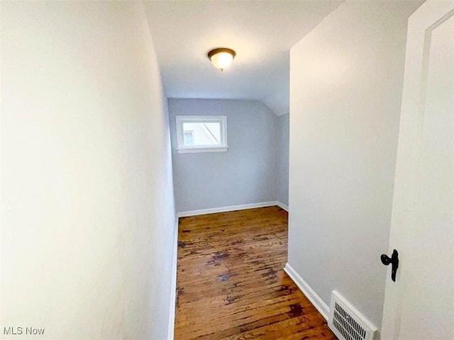 additional living space featuring dark wood-type flooring and vaulted ceiling