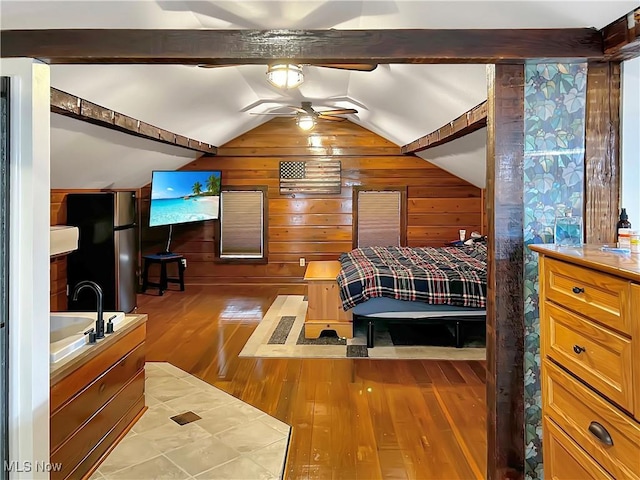 bedroom with wood walls, sink, vaulted ceiling, light hardwood / wood-style flooring, and stainless steel fridge