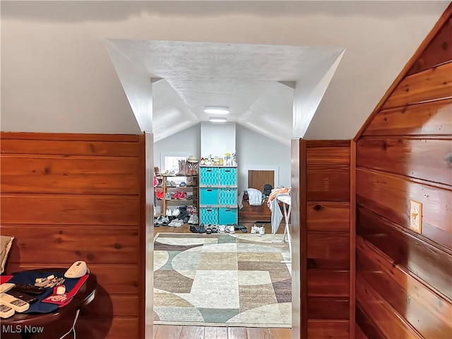 bedroom with wood-type flooring, a textured ceiling, and vaulted ceiling