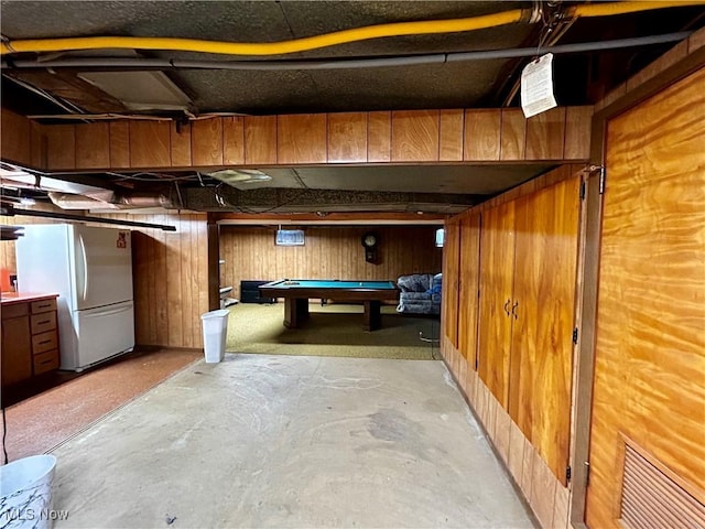 basement with white fridge, pool table, and wood walls