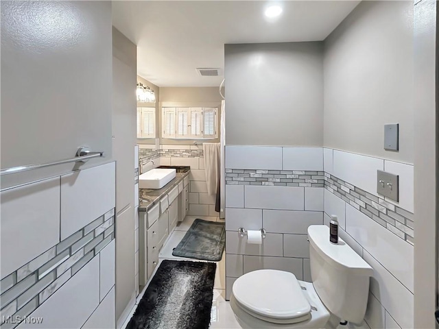 bathroom featuring tile patterned floors, vanity, tile walls, and toilet