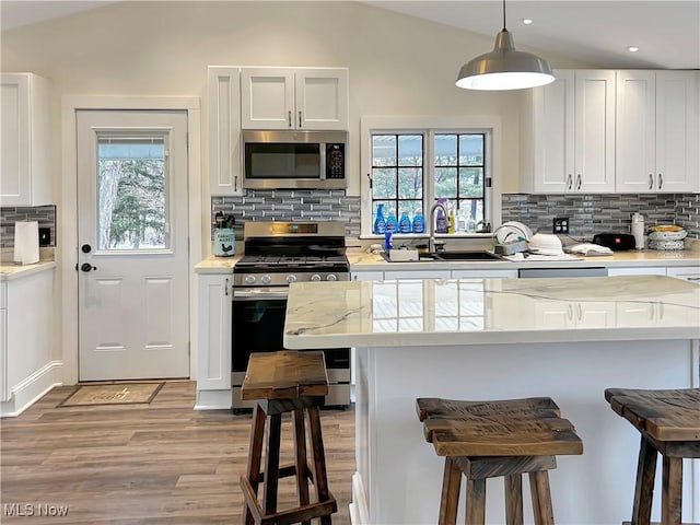 kitchen featuring white cabinetry, stainless steel appliances, and lofted ceiling