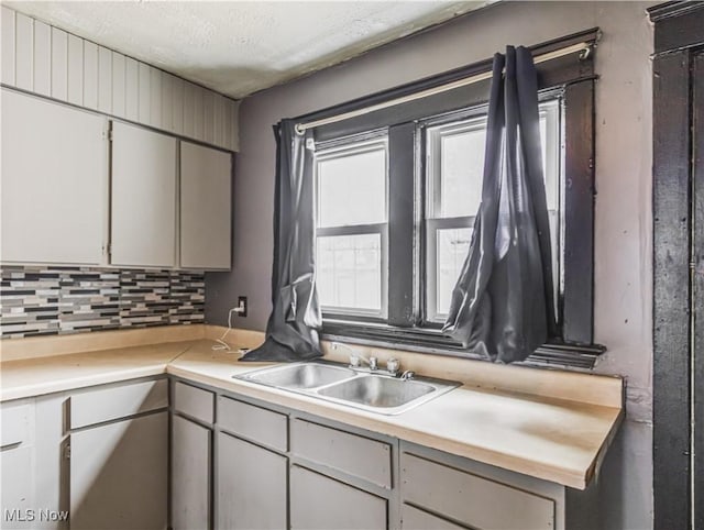 kitchen with backsplash, sink, and a textured ceiling