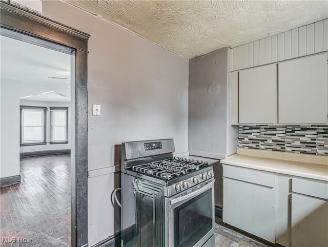 kitchen featuring decorative backsplash, gas range, a textured ceiling, and light hardwood / wood-style floors