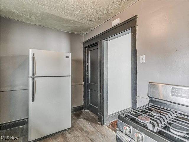 kitchen with stainless steel range with gas cooktop, white fridge, and wood-type flooring