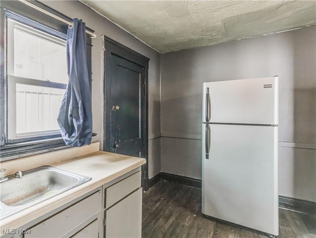 kitchen with dark hardwood / wood-style flooring, stainless steel refrigerator, and sink