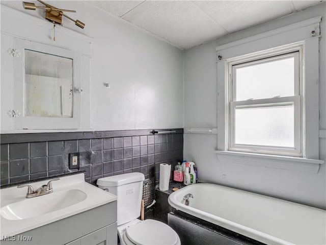 bathroom with a washtub, vanity, toilet, and backsplash