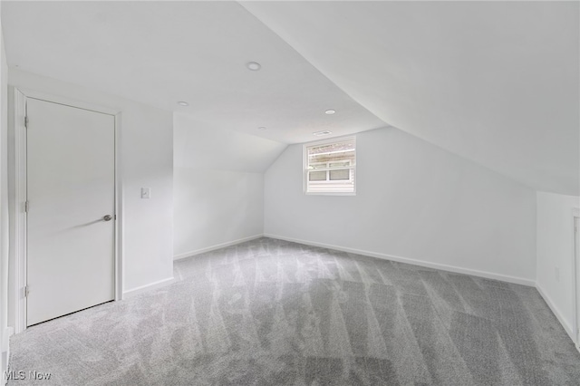 additional living space featuring light carpet and vaulted ceiling