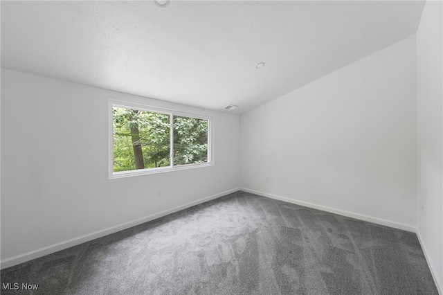 unfurnished room featuring dark colored carpet and lofted ceiling