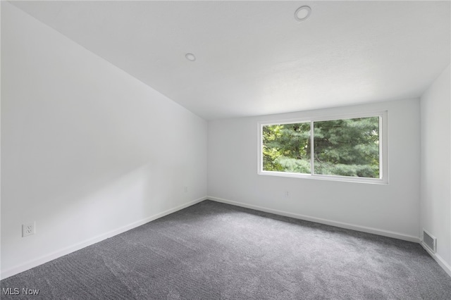 carpeted spare room featuring lofted ceiling