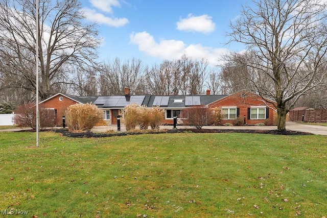 ranch-style home featuring a front lawn and solar panels