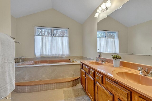 bathroom featuring a bathtub, vanity, lofted ceiling, and tile patterned flooring