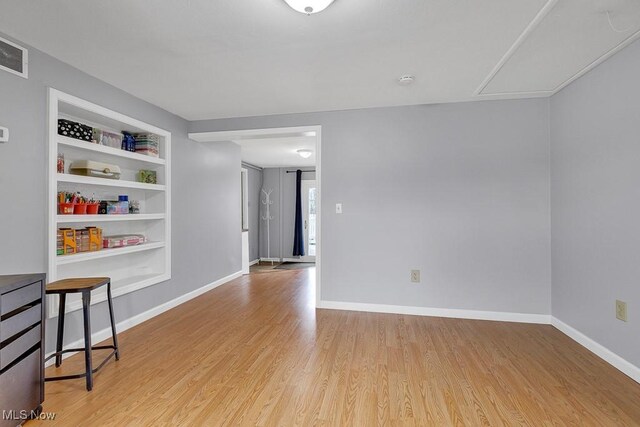 empty room featuring built in features and light wood-type flooring