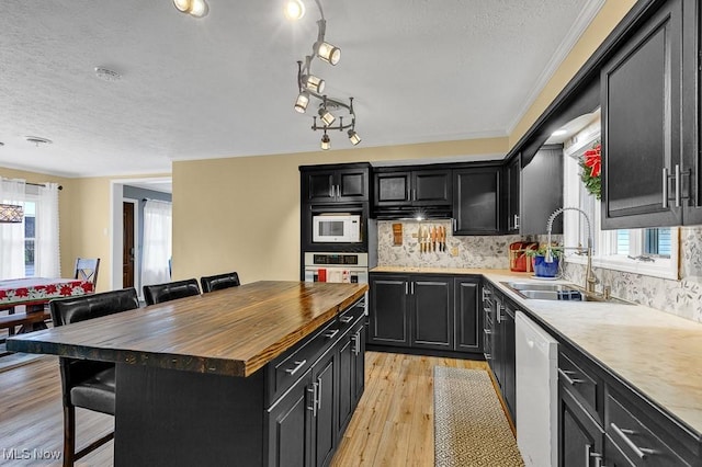 kitchen with plenty of natural light, a kitchen island, white appliances, and sink