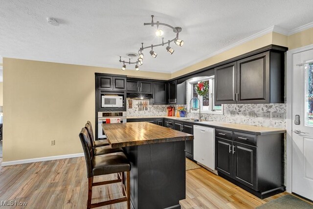 kitchen with plenty of natural light, a center island, wooden counters, and white appliances