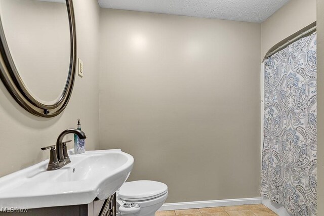 bathroom with tile patterned floors, vanity, a textured ceiling, and toilet