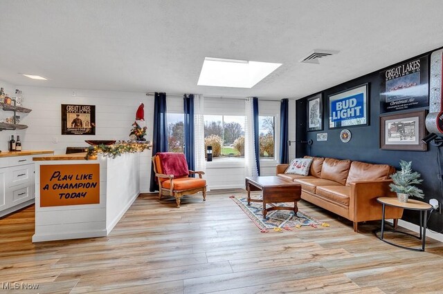 living room featuring a skylight and light hardwood / wood-style flooring