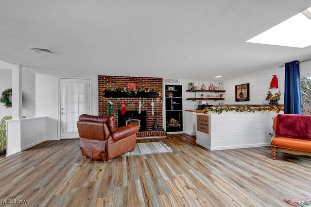 living room with a skylight, a fireplace, and light hardwood / wood-style floors