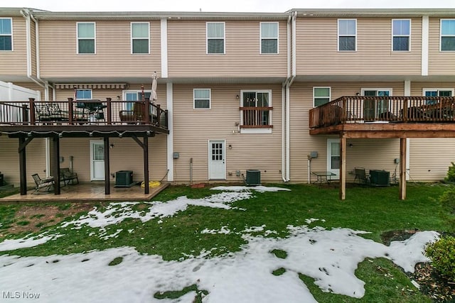 snow covered back of property featuring central air condition unit, a yard, and a deck