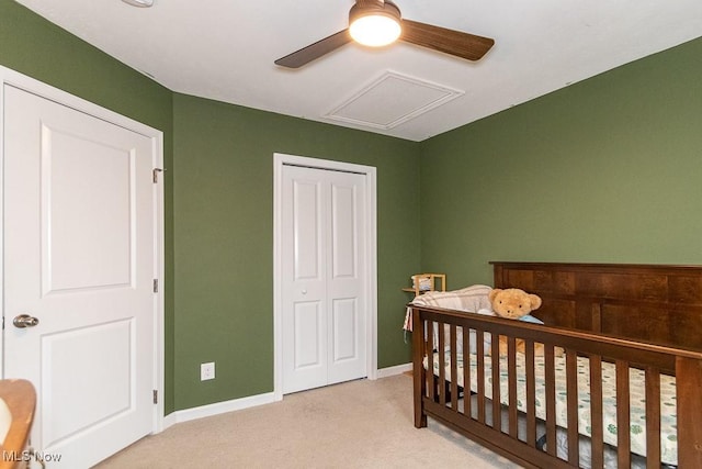 bedroom featuring ceiling fan, a closet, light carpet, and a crib