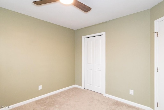 unfurnished bedroom featuring ceiling fan, light carpet, and a closet