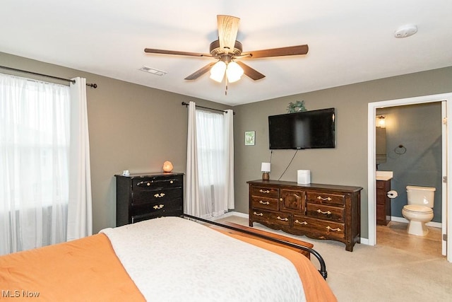 carpeted bedroom with ensuite bathroom and ceiling fan