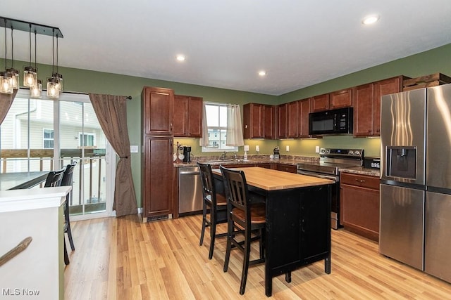 kitchen featuring pendant lighting, a center island, light wood-type flooring, and stainless steel appliances