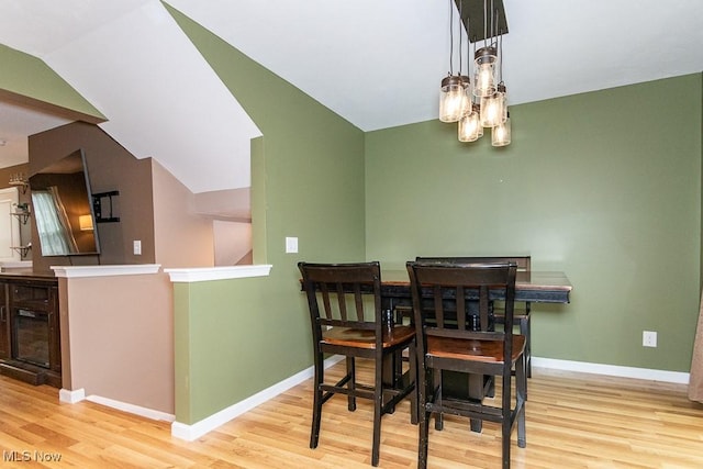 dining space with light wood-type flooring and vaulted ceiling