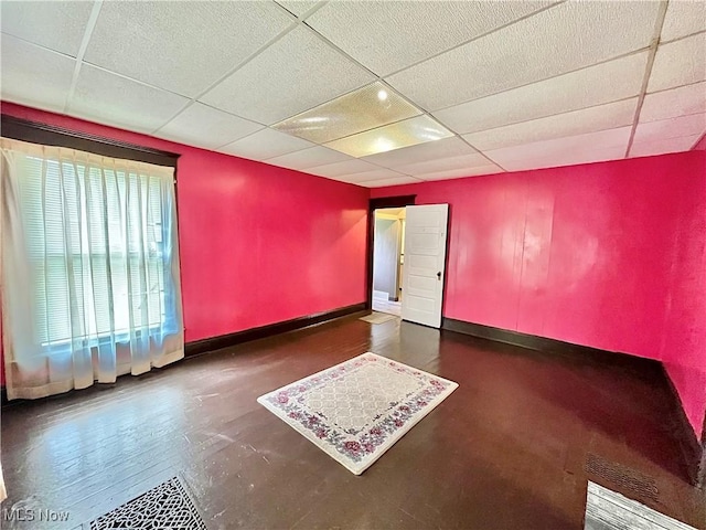 unfurnished room featuring dark hardwood / wood-style flooring and a paneled ceiling